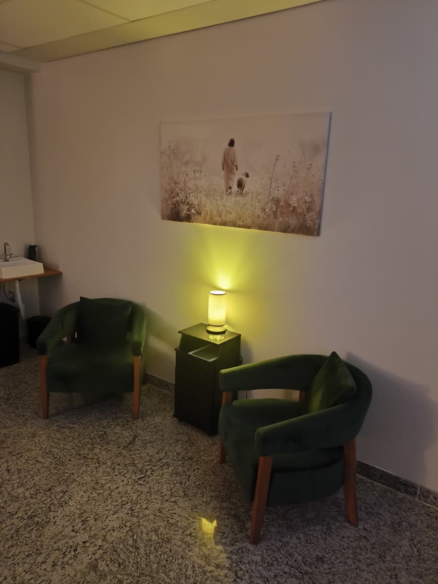 Espaço de espera aconchegante com poltronas verdes e luz suave